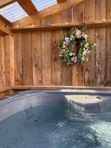 a hot tub with a wreath of flowers on a wooden wall at Chalet Le Merlot in Mandeville