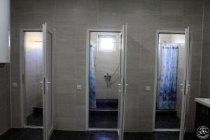 bagno con 2 box doccia con tende blu di KbH-Karakol based Hostel a Karakol