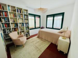 a bedroom with a bed and a chair and bookshelves at NEW - Casa Palamós - Charming historical home with patio, in the heart of the old town, 100m from beach in Palamós