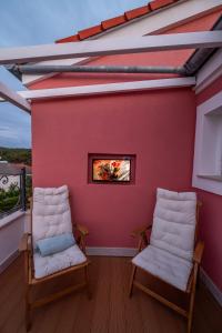 two chairs on a balcony with a red wall at Captain's Escape - Spa City View in Mali Lošinj