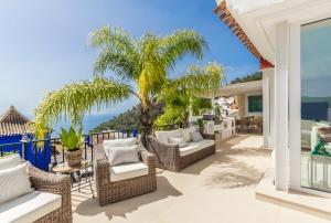 a patio with wicker chairs and a palm tree at Los Altos in Almuñécar