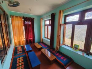 a room with windows and a table and benches at Gremuspa Homestay in Kyelang