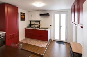 a kitchen with red cabinets and a table and a kitchen at I Masselli Home - Appartamento in villa in Trezzano sul Naviglio