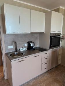 a kitchen with white cabinets and a sink and a microwave at Infinity Sea View Deluxe Apartment in Pomorie