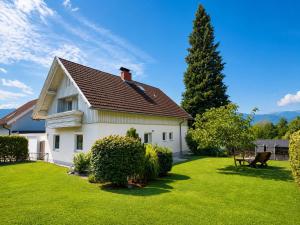 a white house with a green yard at EulenHorst - Ferienhaus in Seeboden am Millstätter See mit Sonnenterasse & Bergblick in Seeboden