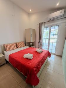 a bedroom with a red bed with two towels on it at Salora Studio-Apartments in Archangelos