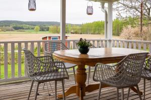 a porch with a wooden table and four chairs at Glaskogen Apartments in Glava