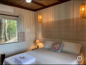 a bedroom with a white bed with a window and a bed sidx sidx at Chalés Casa de Vidro in Alter do Chao