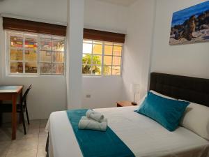 a bedroom with a bed and a desk and two windows at Teresita's House - Suites con cocina privada in Puerto Baquerizo Moreno