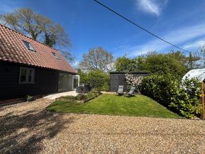 a backyard with a house and a yard withgrass at Ash Tree Lodge in Norwich +7 photos