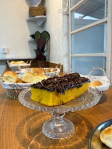 a chocolate cake on a glass plate on a table at Central Suites - Hospedagem Super Econômica in Rio Verde
