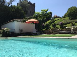 a swimming pool with an umbrella and a table and chair at Castelo Do Castro in Carrazedo