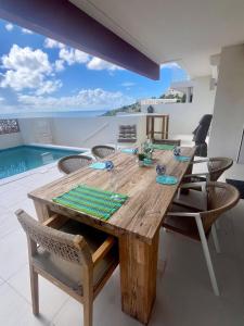 a dining room with a wooden table and a swimming pool at Ben's Gem in Philipsburg