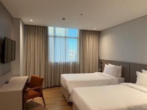 a hotel room with two beds and a window at Hotel Plaza Belmar by HCC in Campo Grande