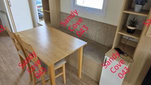 a wooden table and chairs with red signs on it at Sandy cove 043 in Barmouth +2 photos