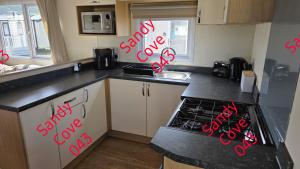 a kitchen with red writing on the counters at Sandy cove 043 in Barmouth