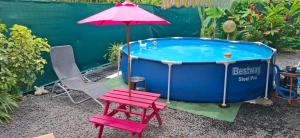 a hot tub with a chair and an umbrella at Méline in Baie-Mahault