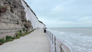 a walkway next to a wall next to the ocean at Reverie Escape by Halisi in Ramsgate +39 photos