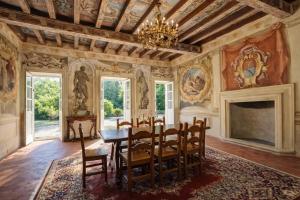 a dining room with a table and chairs and a fireplace at Villa Dorigny Dimora Storica con Affreschi e Giardino in Verona