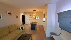 a living room with a couch and a flat screen tv at Golden Sun Apartment Grzybowo in Grzybowo