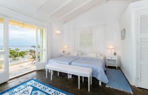 a white bedroom with a bed and a large window at Bay View Hotel in (( Klonátika ))