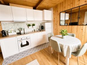 a kitchen with white cabinets and a table with chairs at Le cocon beuillois in Beuil
