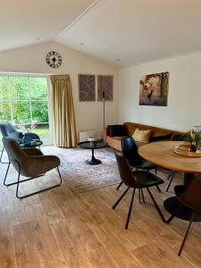 a living room with a couch and a table and chairs at Chalet de Veluwe Europarcs in Otterlo