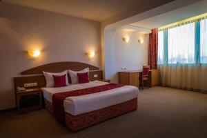 a hotel room with a large bed and a large window at Hotel Sevlievo Plaza in Sevlievo