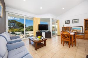 a living room with a blue couch and a dining room at Villa Elena Dorada in Port d'Addaia