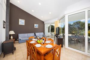a dining room with a table and a couch at Villa Elena Dorada in Port d'Addaia