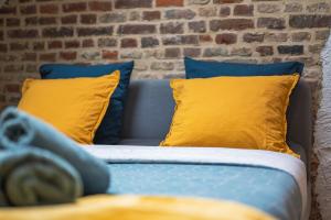 a blue couch with yellow pillows and a brick wall at Le 29 - T2 Calme - Confortable - Centre-ville in Valenciennes