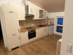 a white kitchen with white cabinets and a window at Monteurwohnung in Runkel