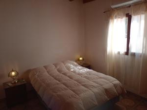a bed in a room with a window and two lamps at Duplex Hermosinda Hospedaje in Chilecito