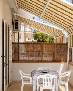 a dining room with a table and white chairs at Appartamenti ABR Porto in Le Castella