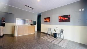 a man standing in a room with two chairs at Central Suites - Hospedagem Super Econômica in Rio Verde