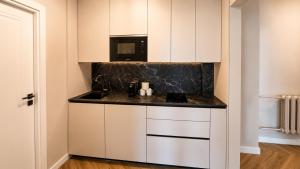 a kitchen with white cabinets and a microwave at Greystone Suites & Apartments in Riga