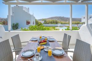 a wooden table with food and orange juice on a balcony at Depis luxury villas naxos in Plaka