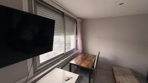 a room with a tv and a table and a window at Appartement 2 Pièces in Annemasse