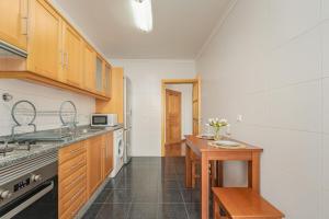 a kitchen with wooden cabinets and a wooden table at One-Bedroom Apartment near Reis Magos Beach in Caniço