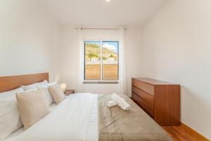 a white bedroom with a large bed and a window at One-Bedroom Apartment near Reis Magos Beach in Caniço