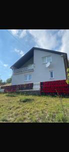 a white house with a red fence in front of it at Rastoder Ponor in Petnjica