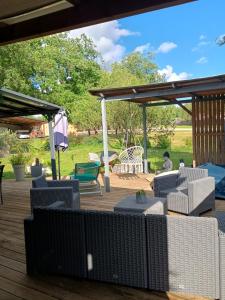 a patio with couches and chairs on a wooden deck at Gite du gachou in Souillac