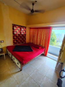 a bedroom with a red bed and a window at AKS Cottage in Yercaud