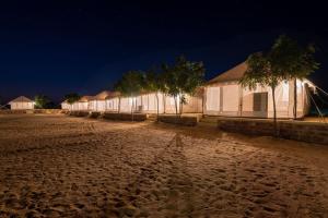 a row of white buildings at night with trees at Hostel Desert Camp Sam in Jaisalmer