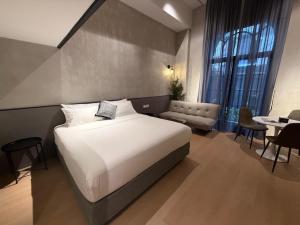 a bedroom with a large white bed and a table at Atelier Hotel Permas in Johor Bahru