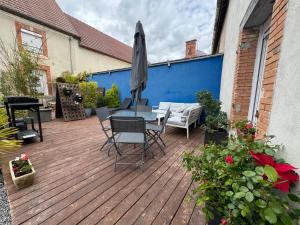 a patio with a table and chairs and an umbrella at Sarments et Bulles in Ambonnay