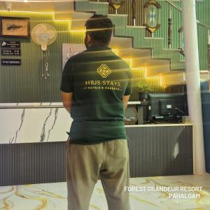 a man standing in a room looking at a staircase at Forest Grandeur Resort in Anantnāg