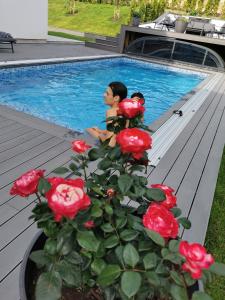 a boy sitting next to a potted plant next to a swimming pool at Villa med pool in Bara