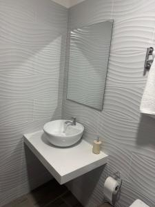 a white bathroom with a sink and a mirror at Hostal Gardner in Puerto Ayora +44 photos
