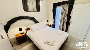 a small bedroom with a white bed and a window at O Palheiro in Biscoitos